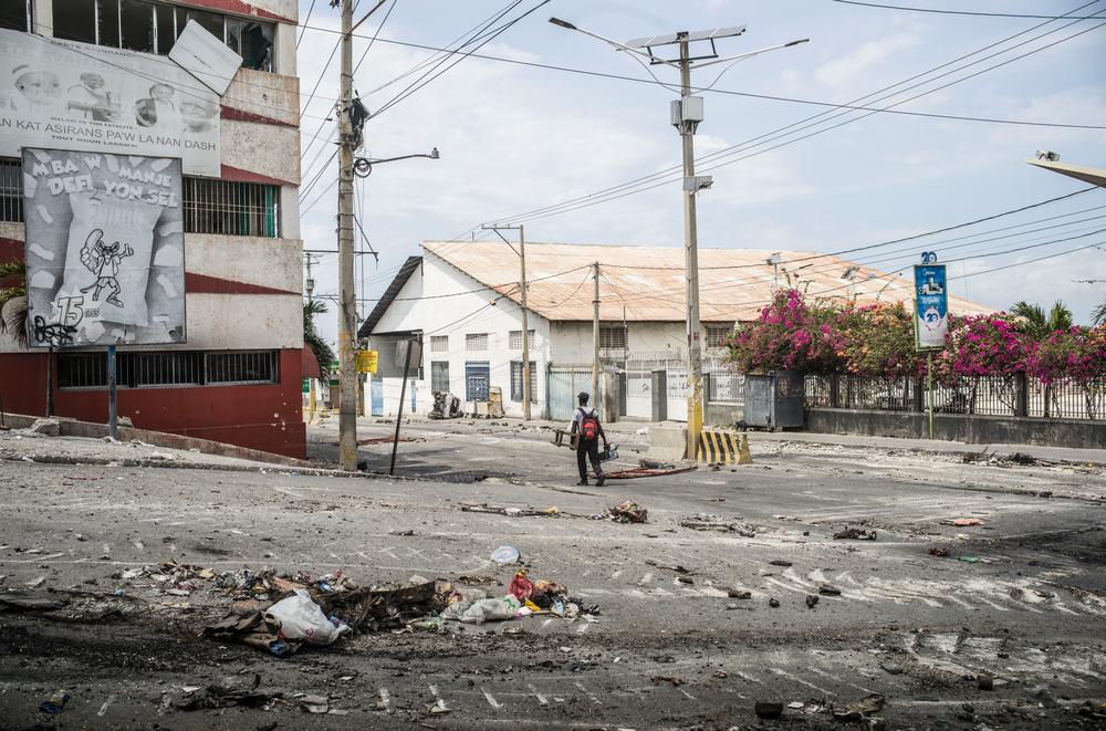 Un homme marche seul dans les rues détruites de Port-au-Prince après les combats entre les groupes armés et les forces de police. Haïti, mars 2024. © Corentin Fohlen/ Divergence