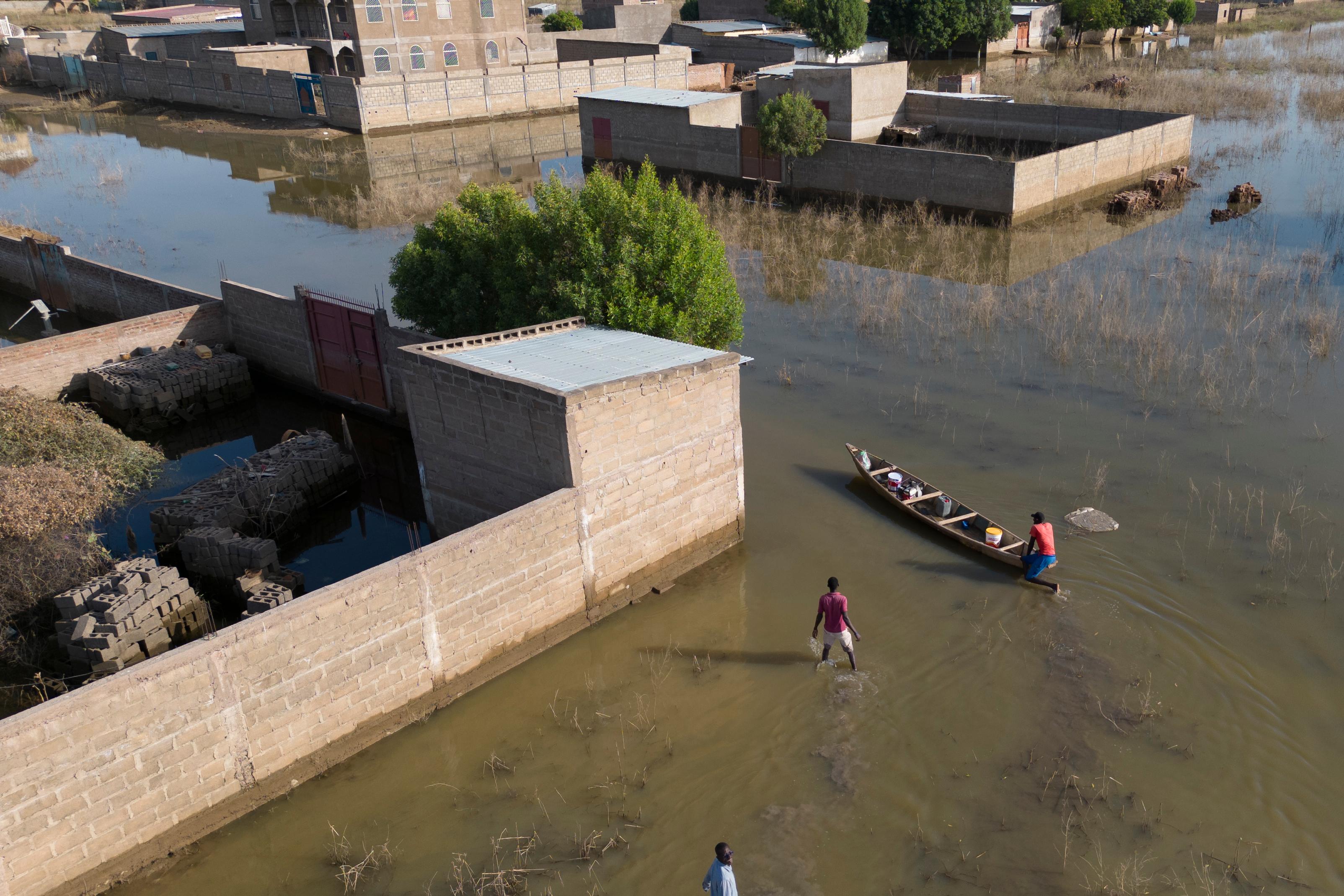 Tchad. N'Djamena. Quartier de Didangali, banlieue sud de la capitale. Trois hommes utilisent une embarcation pour tenter de rejoindre leur domicile afin de récupérer des couvertures et quelques ustensiles.